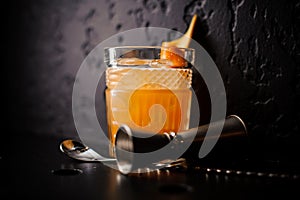 Orange cocktail in crystal glass with bar spoon and jigger