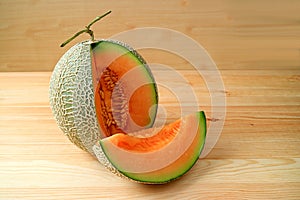 Orange Color Fresh Ripe Juicy Muskmelon with a Slice from Whole Fruit Isolated on a Wooden Table