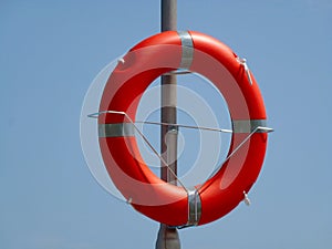 Orange color plastic lifebuoy or life preserver ring mounted on aluminum pole