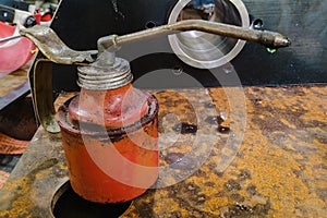 an orange-colored oil can stands on a large part at the workplace of a locksmith-welder