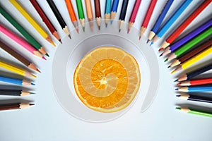 Orange with colored pencils and shavings on a white background