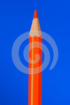 Orange colouring crayon pencil isolated on blue background.