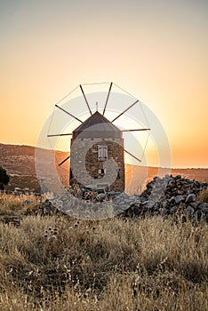 Orange colours of sunset time, one old windmill in the mountains