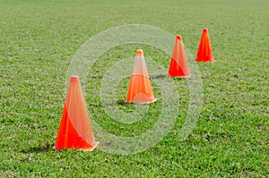 Orange cone markers on the green grass