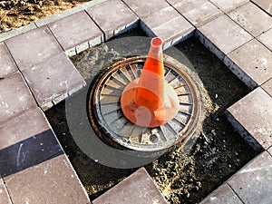 An orange cone stands on a dangerous section of the road. the identification mark in a bright, distinctive color stands in a hole