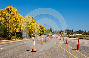 Traffic sign with flags reading Utilitary Work Ahead with traffic cones on road. Row of Traffic cone in the road repair photo