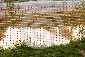 Orange construction fence mesh. A warning sign on the progress of construction work at the reservoir