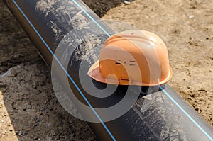 Orange construction helmet lying on a plastic water pipe