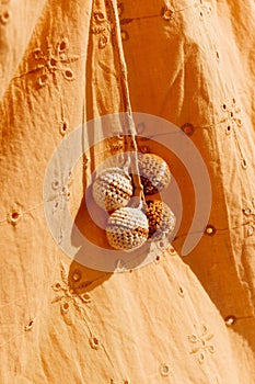 Orange cotton shirt with four multi-colored wool pom poms attached