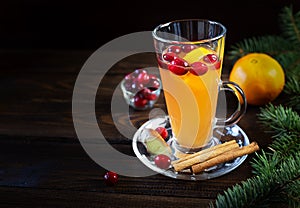Orange and cranberry non-alcoholic punch with orange slices and spices on a dark wooden table
