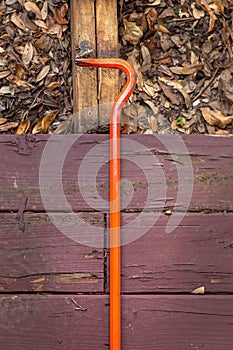 An orange crowbar on an old wooden plank