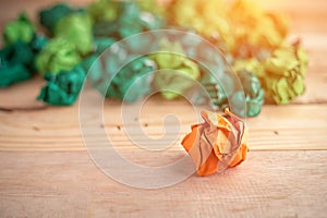 Orange crumpled paper among the green paper