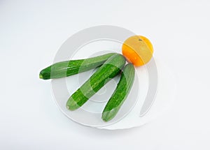 Orange, cucumber on white background, white plate