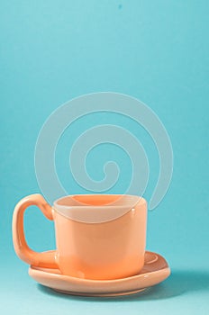 orange cup on a blue background/orange cup with a saucer on a blue background