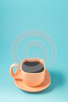 orange cup coffee on a blue background/ orange cup with a saucer full of black coffee on a blue background