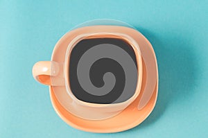 orange cup coffee on a blue background/orange cup with a saucer full of black coffee on a blue background, top view