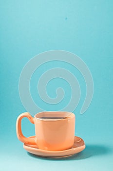 Orange cup with espresso on a blue background/orange cup with black coffee on a blue background