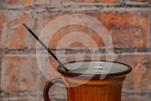 Orange cup with fragnant stick and red brick wall background