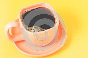 orange cup on a yellow background/orange cup of espresso with a skin on a yellow background, top view