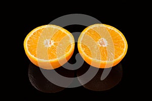 Orange cut into two pieces, on a black background.