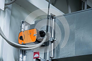 Orange damper actuator installed on the ductwork of the central ventilation system photo