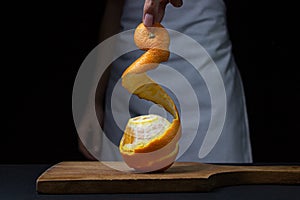 Orange on a dark background. The chef is peeling an orange.