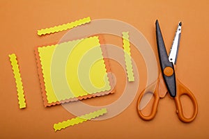 Orange and decorative scissor on pastel orange background. place