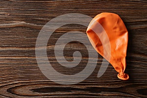 Orange deflated balloon on wooden background