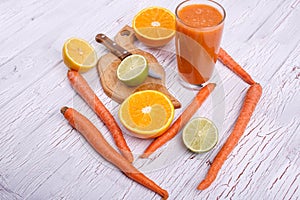 orange detox coctail with oranges,lime and carrots lies on white