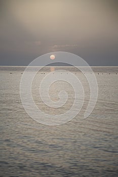 Orange disk of the sun setting over the sea during sunset on the Mediterranean sea