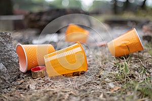 Orange disposable Plastic glass or cups used for drinking water in a bin - Environmental problem concept. Non-compostable waste