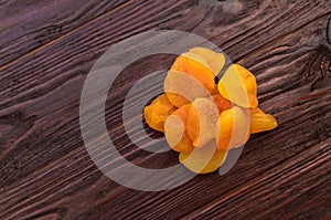 Orange dried apricot on a dark wooden table textural