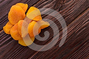 Orange dried apricot on a dark wooden table textural