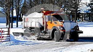 Orange dump truck with plow blade hauls a load of snow after several winter snow storms