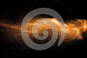 Orange dust particles explosion on black background.