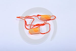 Orange earplug on thread. Earplug to reduce noise on a white background .