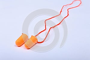 Orange earplug on thread. Earplug to reduce noise on a white background .