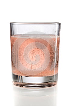 Orange effervescent tablet in a glass of water.