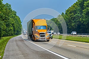 Orange Eighteen-Wheeler In Traffic On Interstate Highway