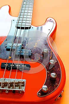 Orange electric bass guitar on orange background