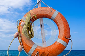 Orange emergency lifebuoy on a pebbly sea beach, close up