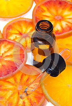 Orange essential oil in amber bottle with red oranges