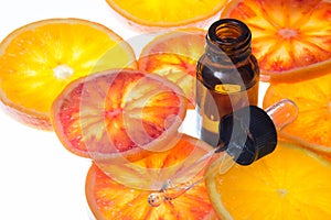 Orange essential oil in amber bottle with red oranges