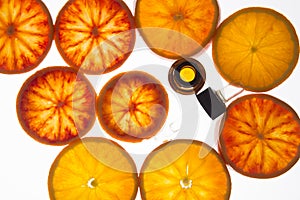 Orange essential oil in amber bottle with red oranges