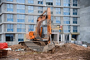 Orange excavator at building under construction. Ð¡onstruction vehicle used to excavate or move large objectsÑŽ.