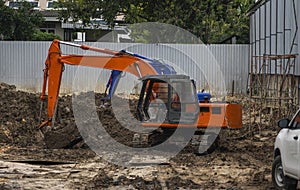 Orange excavator on a ground against blue sky and sea for a works on construction site. Small tracked excavator standing