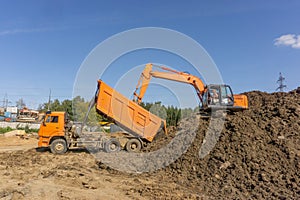 Orange excavator loads the land