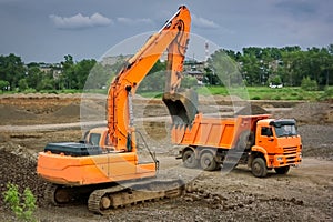Orange excavator and orange dump truck at a construction site