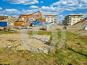 Orange excavator on the site of bilding, dismantling of the building