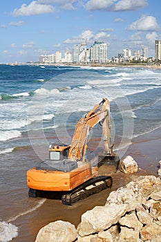 Orange excavator working on the Tel-Aviv beach in Israel